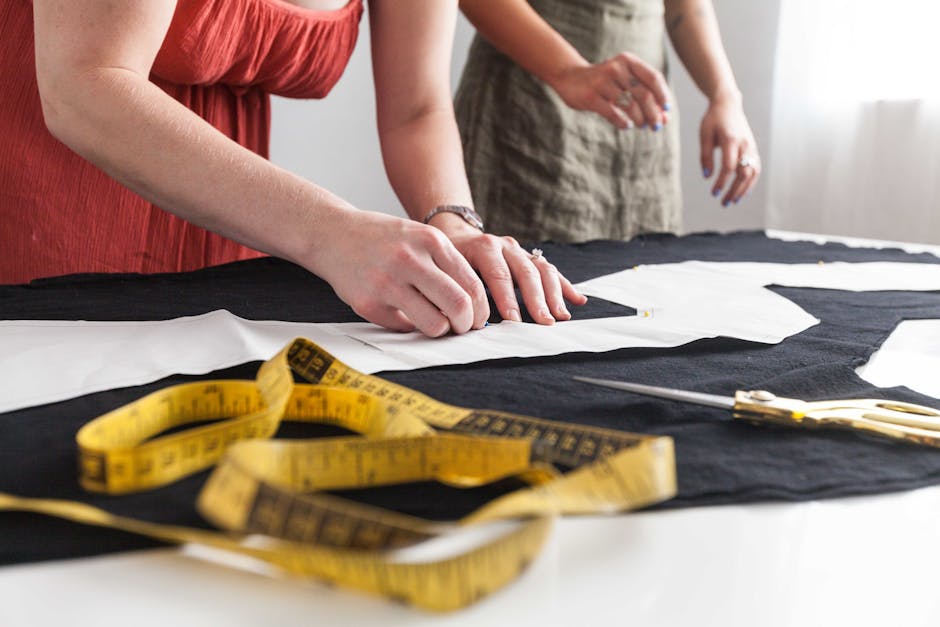Women working on sewing patterns with measuring tape and fabric.