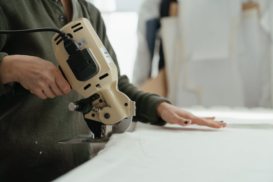 Close-up of hands using a rotary cutter to cut fabric in a sewing workshop.